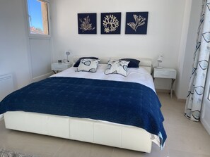 Une chambre bien rangée, avec un lit, des tables de chevet et des œuvres d’art accrochées au mur.