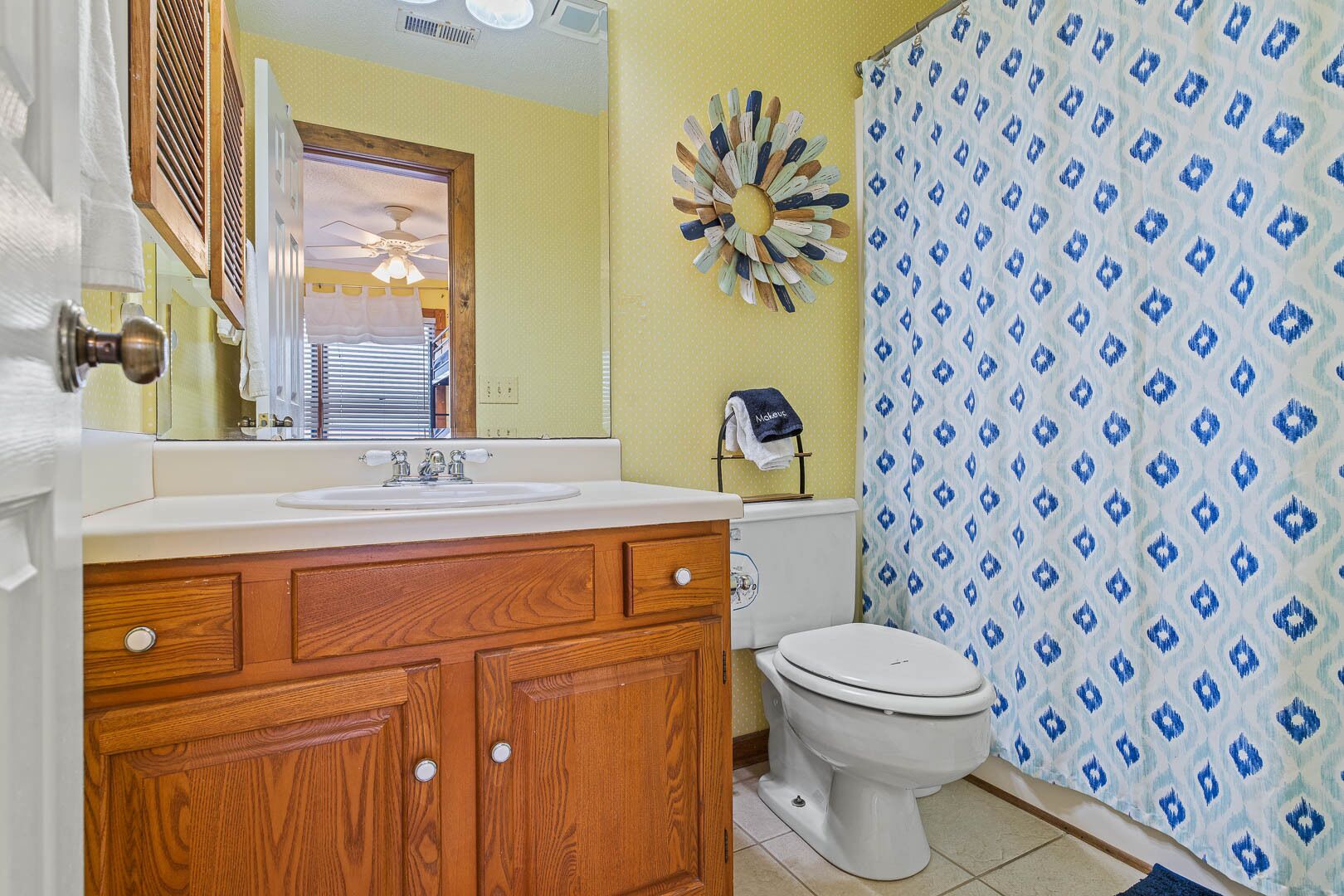 A bathroom with a wooden vanity, a white toilet, and a shower curtain with a geometric pattern.