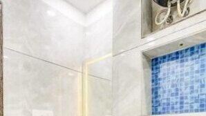 Un baño moderno con un lavamanos blanco, un espejo y una zona de ducha con azulejos azules.