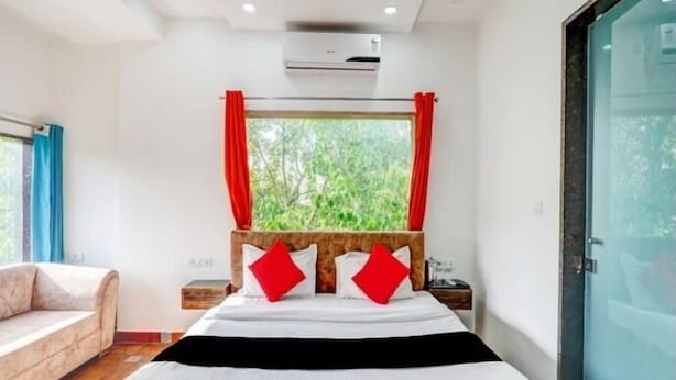 Un dormitorio moderno con una cama grande, cabecera de madera y una ventana con cortinas rojas.