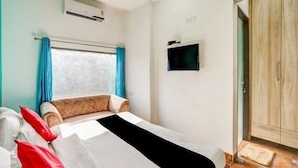 Un dormitorio con una cama, un televisor montado en la pared y un armario.