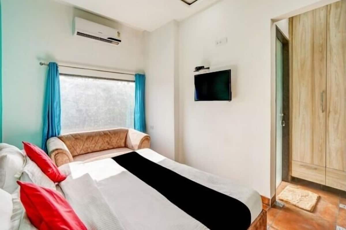A bedroom with a bed, a TV mounted on the wall, and a wardrobe.