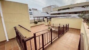 Eine Dachterrasse mit Fliesenboden, Holzgeländer und Kübelpflanzen.