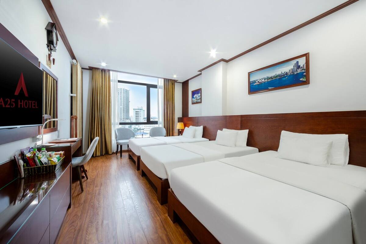 A hotel room with two beds, a desk with a TV, a window with a city view, and a painting on the wall.