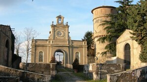 A historic building with a central tower and arched entrance, surrounded by stone walls and vegetation. - La Casetta di Mimmi (Castel Viscardo)
