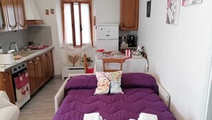 A bedroom with a purple bedspread, two white towels, a wooden chair, and a small table with a vase. - La Casetta di Mimmi (Castel Viscardo)