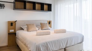A modern bedroom with a large bed, wooden headboard, and a built-in shelf above the bed. - Evancy Trésors d'Opale (Camiers)