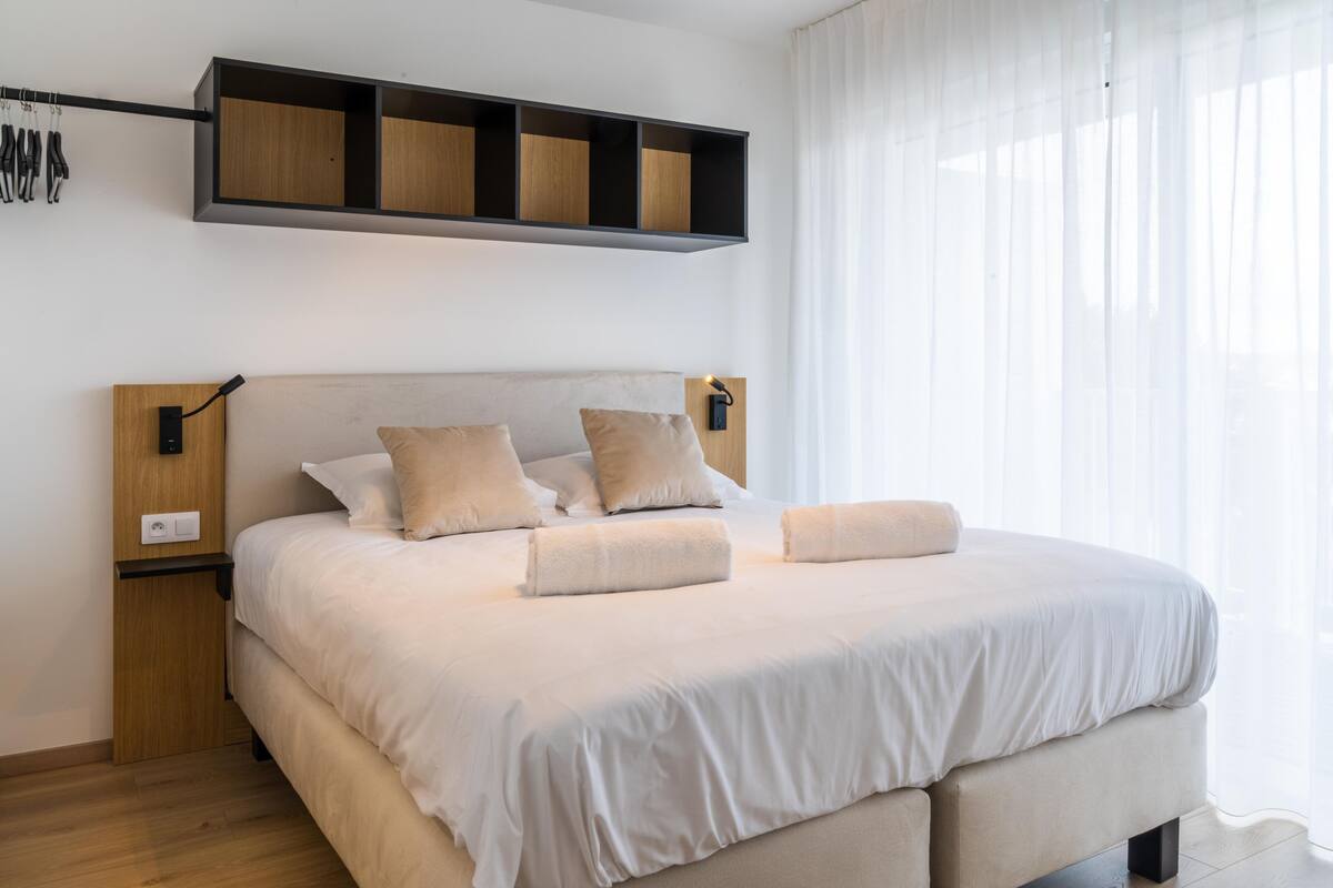 Ein modernes Schlafzimmer mit einem großen Bett, einem Holz-Kopfteil und einem eingebauten Regal darüber.