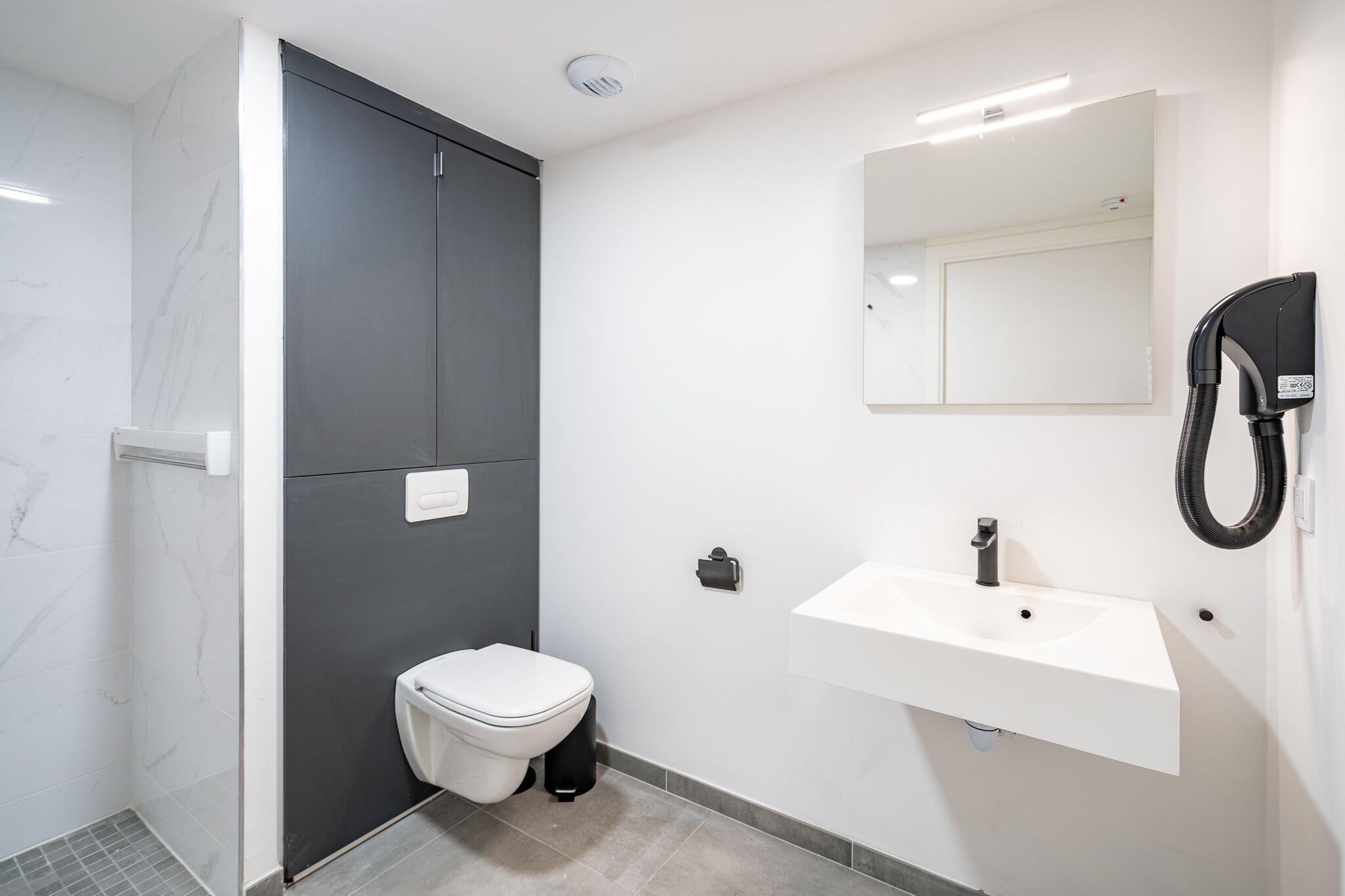Een moderne badkamer met toilet, wastafel en douche.
