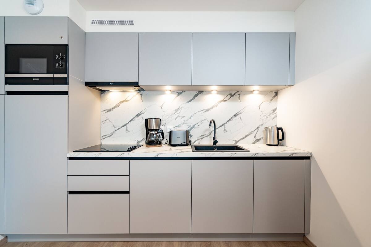 Eine moderne Küche mit Einbau-Mikrowelle, Kaffeemaschine und Spüle.