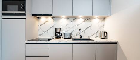 Una cucina moderna con forno a microonde integrato, macchina del caffè e lavandino.