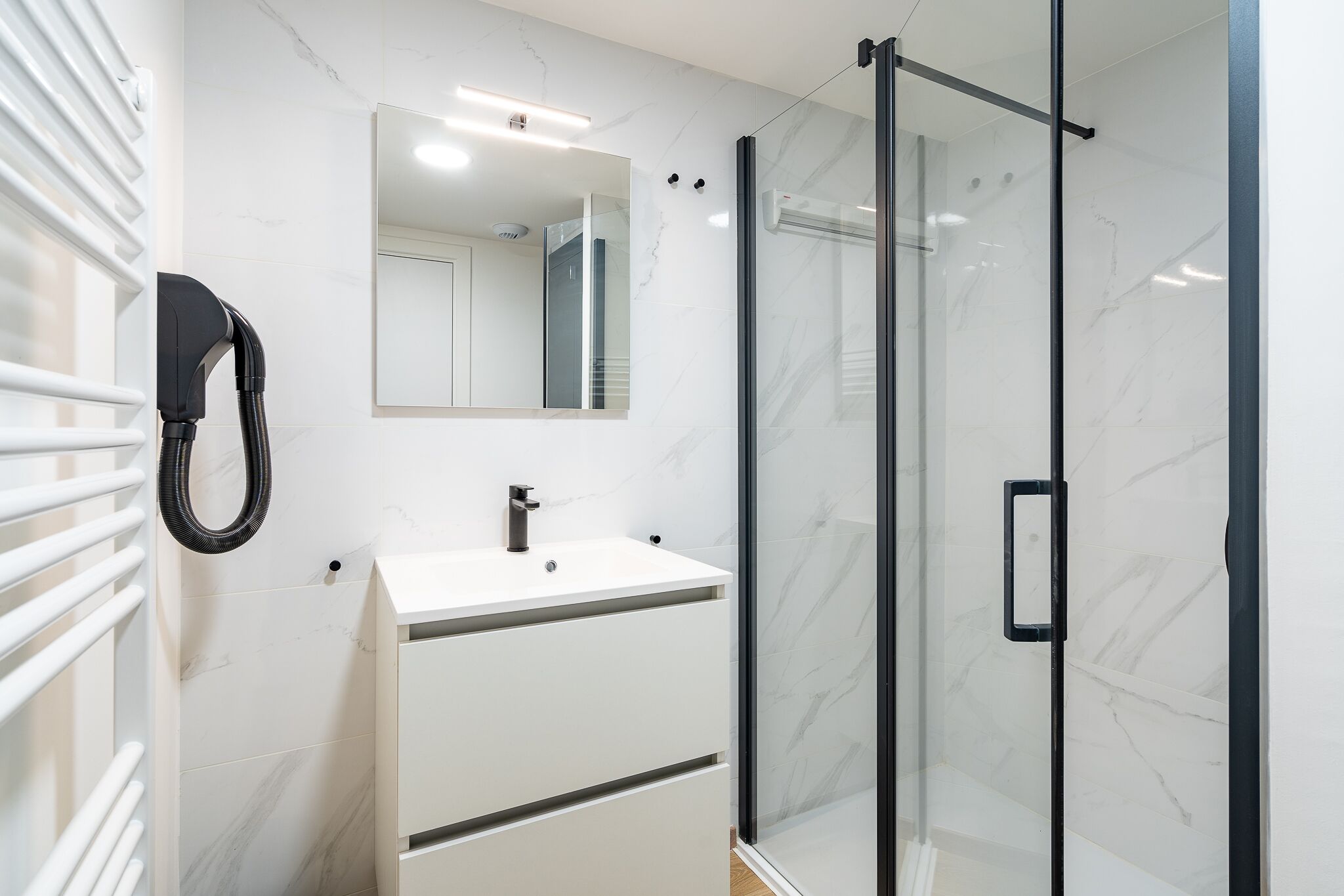 A modern bathroom with a glass-enclosed shower, a white sink, and a mirror above the sink.