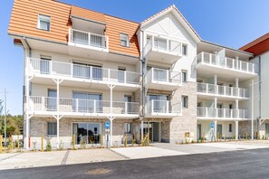 A multi-story hotel with balconies, brick facade, and a clear sky. - Evancy Trésors d'Opale (Camiers)
