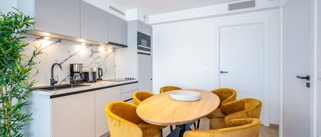 Cocina moderna con isla central, electrodomésticos integrados y zona de comedor con sillas amarillas.