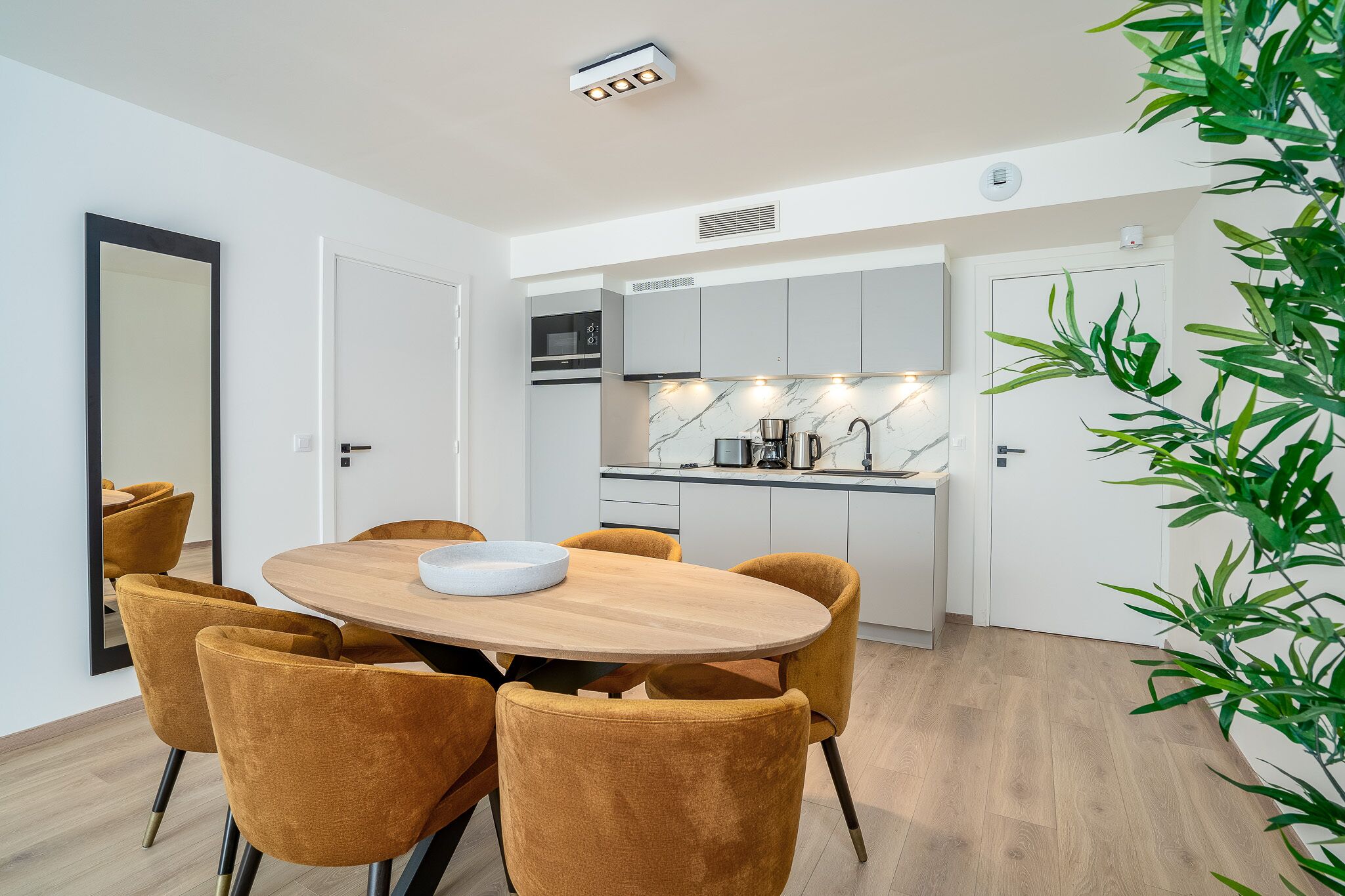 A modern kitchen with white cabinets, a marble backsplash, and a built-in oven.