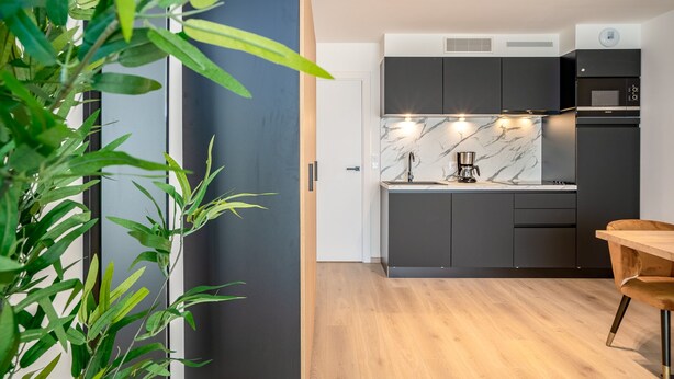 A modern kitchen with dark cabinetry, a marble countertop, and built-in appliances. - Evancy Trésors d'Opale (Camiers)