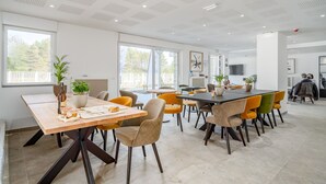A modern dining area with multiple tables and chairs, large windows, and potted plants. - Evancy Trésors d'Opale (Camiers)
