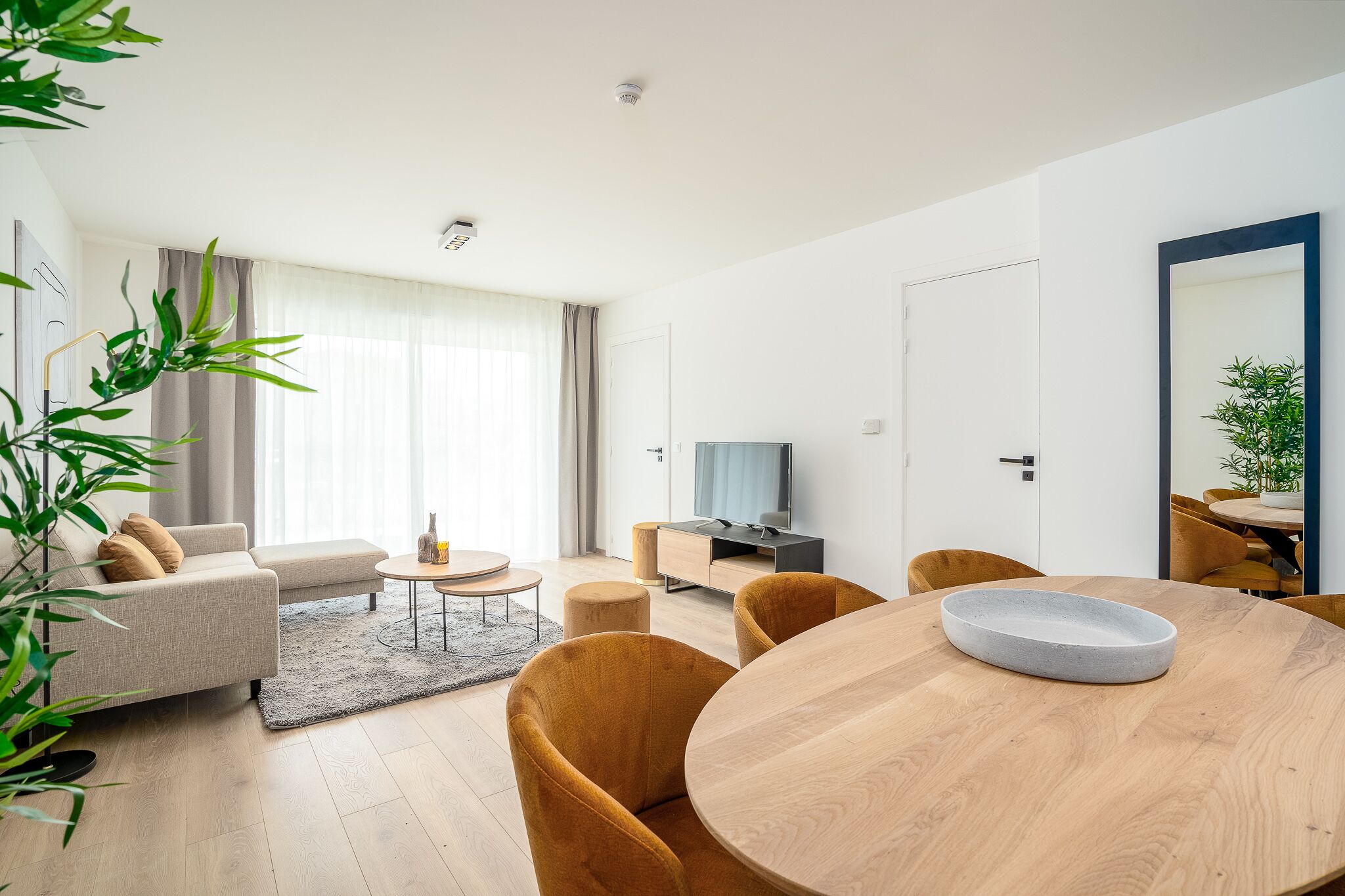 A modern living room with a sofa, coffee table, and dining table.
