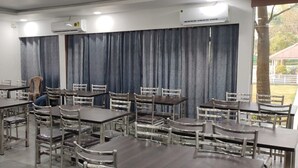 A conference room with multiple tables and chairs, air conditioning units, and a view of the outdoors. -  Royal Hills Resort (Mawal)