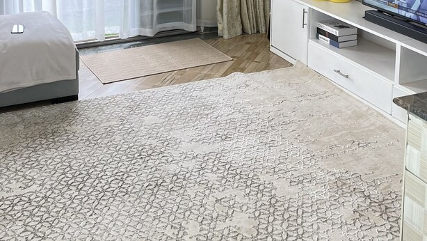 Una camera da letto con un letto, una TV, un armadietto bianco e un'ampia finestra con tende.