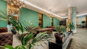 A spacious lobby with a modern chandelier, leather seating, and potted plants. - King David Residences (Tbilisi)
