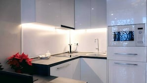 A modern kitchen with white cabinets, a Bosch microwave, and a sink. - King David Residences (Tbilisi)