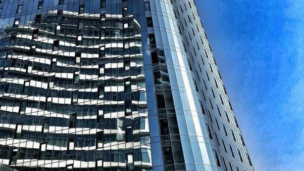 A modern high-rise building with a curved facade and reflective glass windows. - King David Residences (Tbilisi)