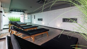 A modern spa room with massage tables, a reception area, and a large mirror.