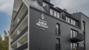 A modern building with balconies and a sign reading "APARTMENT KOO BRZEGU BY NICKEL".
