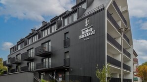 A modern apartment building with multiple balconies and a staircase leading to the entrance.