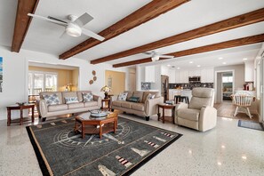 A spacious living room with a large coffee table, two sofas, and a high ceiling with exposed beams.
