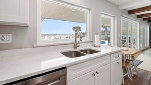 A modern kitchen with a large window, a stainless steel sink, and a view of the beach. - Ponce Inlet Beach House (Ponce Inlet)