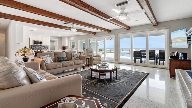 A spacious living room with a large sofa, a coffee table, and a view of the ocean through large sliding doors. - Ponce Inlet Beach House (Ponce Inlet)