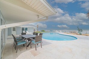 A pool area with a table and chairs, a covered patio, and a view of the ocean. - Gorgeous 4 bedroom oceanfront house with pool - Ponce Inlet Beach House (Ponce Inlet)