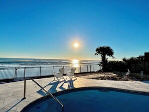A swimming pool with a view of the ocean and sunset.