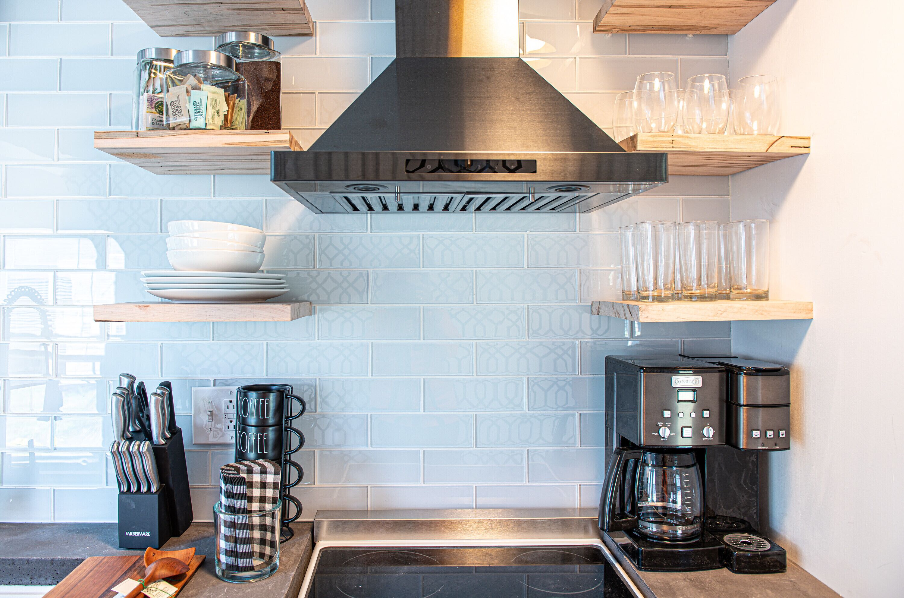 A kitchen with a stainless steel range hood, a coffee maker, and various kitchen utensils on the counter.
