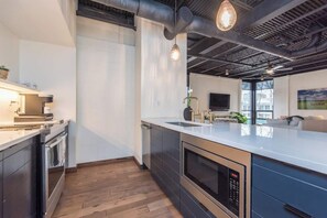 A modern kitchen with a large island, stainless steel appliances, and pendant lighting.