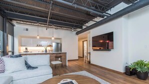 A modern living room with a sofa, coffee table, and a kitchen in the background.
