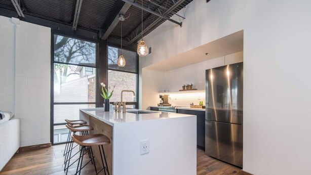 A modern kitchen with a central island, stainless steel appliances, and wooden flooring.