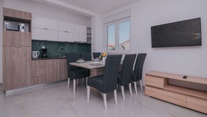 Ett modernt kök med matplats, en platt-TV och ett träskåp.