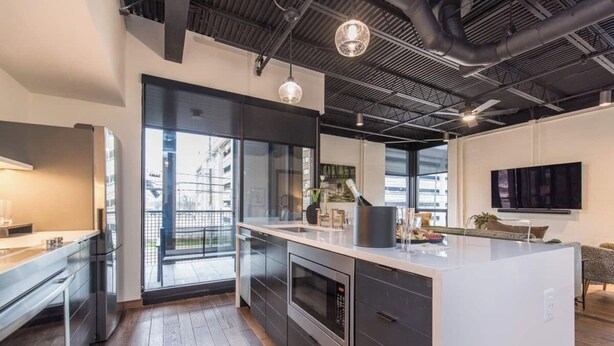 Une cuisine moderne dotée d’un grand îlot central, d’appareils électroménagers intégrés et d’une grande fenêtre offrant une vue sur la ville.