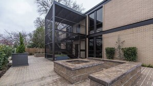 Une terrasse extérieure moderne avec un escalier en métal, des jardinières en pierre et un mur en briques.