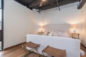 A bedroom with a bed, two nightstands, two lamps, and two foldable chairs. - This serviced apartment is a 2 bedroom(s), 2 bathrooms, located in Lexington, KY. (Lexington)