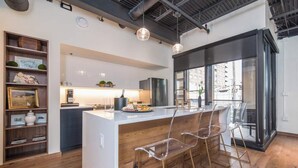 Une cuisine moderne dotée d’un îlot central, de tabourets de bar et offrant une vue sur l’extérieur.