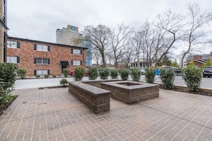 Stroll through the serene courtyard, surrounded by lush greenery and a beautifully designed brick building.