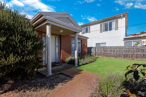 A two-story house with a covered porch, a fenced backyard, and a well-maintained lawn.
