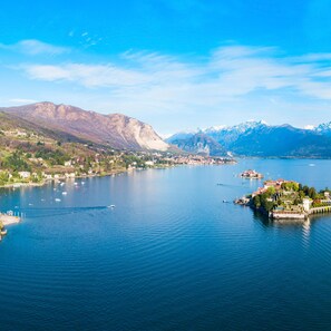 A panoramic view of a lake with a town on the shore, mountains in the background, and a small island with buildings. - Residenza Oleandro Lake View Luino Center (Luino)