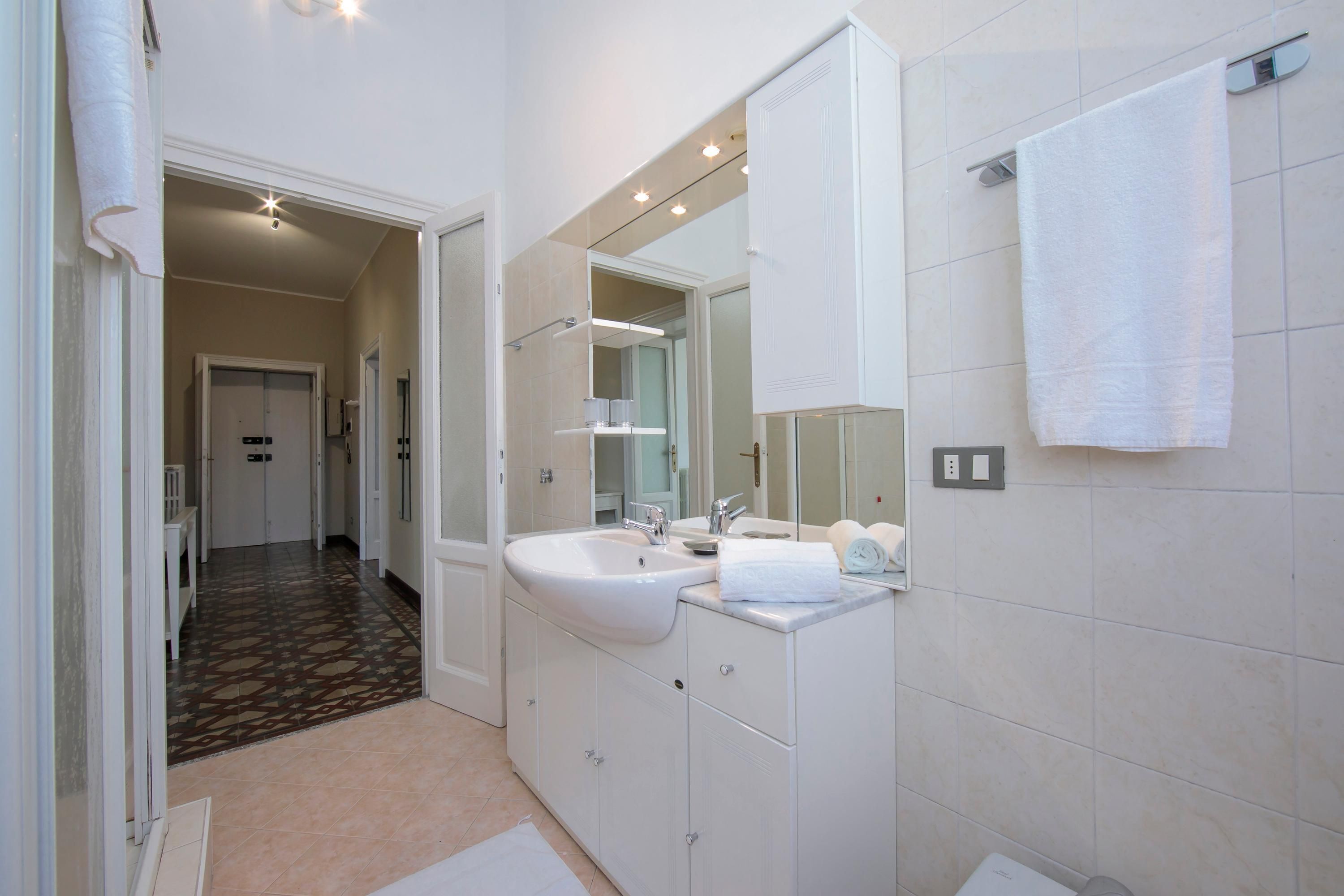 A modern bathroom with two sinks, a large mirror, and a walk-in shower.