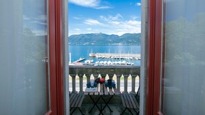 Un balcone con vista su un porto turistico e montagne.