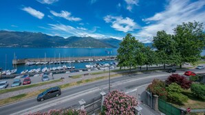 Una marina con imbarcazioni ormeggiate, una strada con auto e montagne sullo sfondo.
